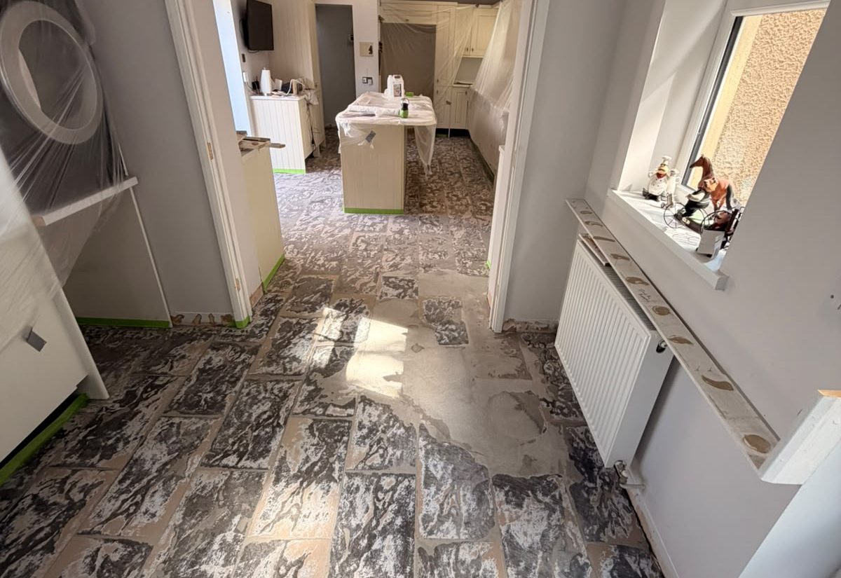 Kitchen floor before resin installation, ripped-up tiles and bare screed